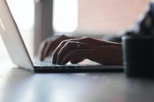 an adult's hands rest on a laptop keyboard
